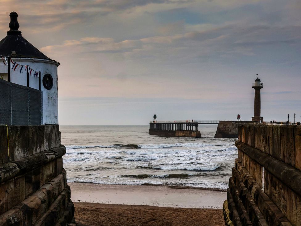 A view of a pier and lighthouse with water at Sail Away, 17 Union Mill in Whitby