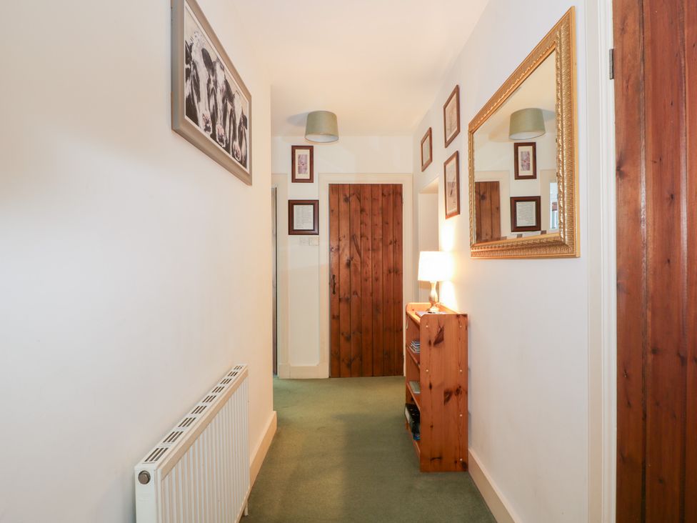 A hallway with a wooden door and a lamp on a shelf at Strathannan in Moffat