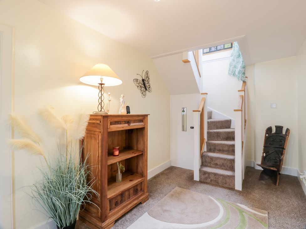 A hallway with a bookshelf and staircase at Strathannan in Moffat