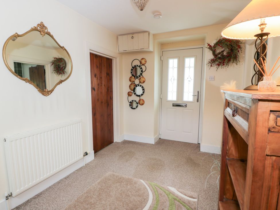 A hallway with a mirror and wooden door at Strathannan in Moffat