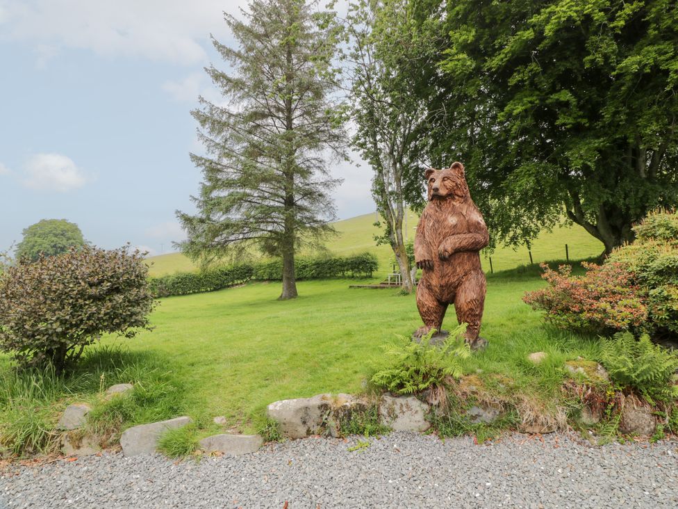 A bear statue on grass with trees and bushes at Strathannan in Moffat
