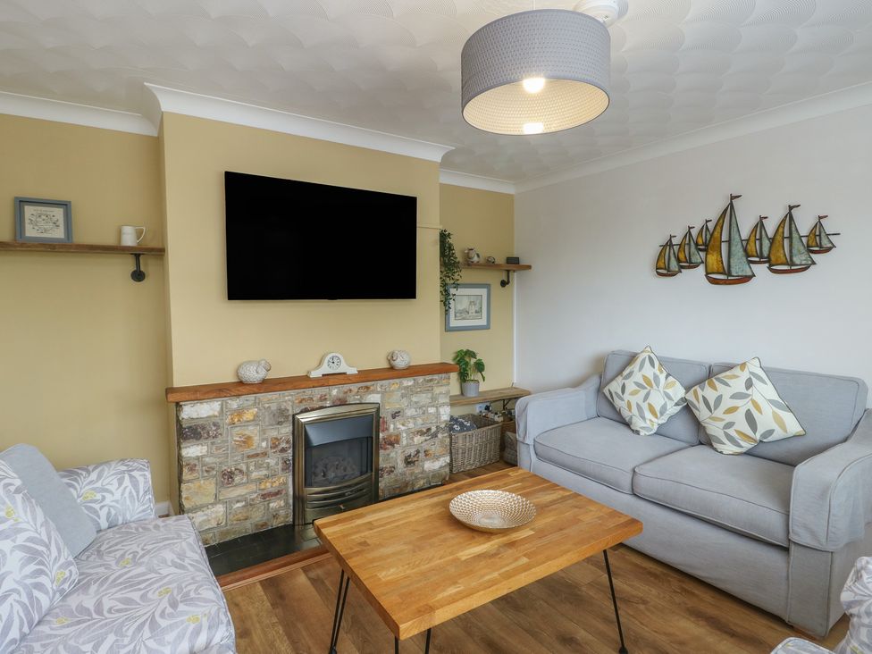 A living room with a sofa, coffee table, and television at Glasfryn Holyhead