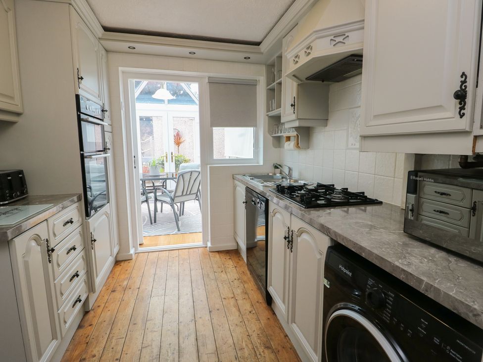 A kitchen with appliances and a door leading to an outdoor area at Glasfryn Holyhead