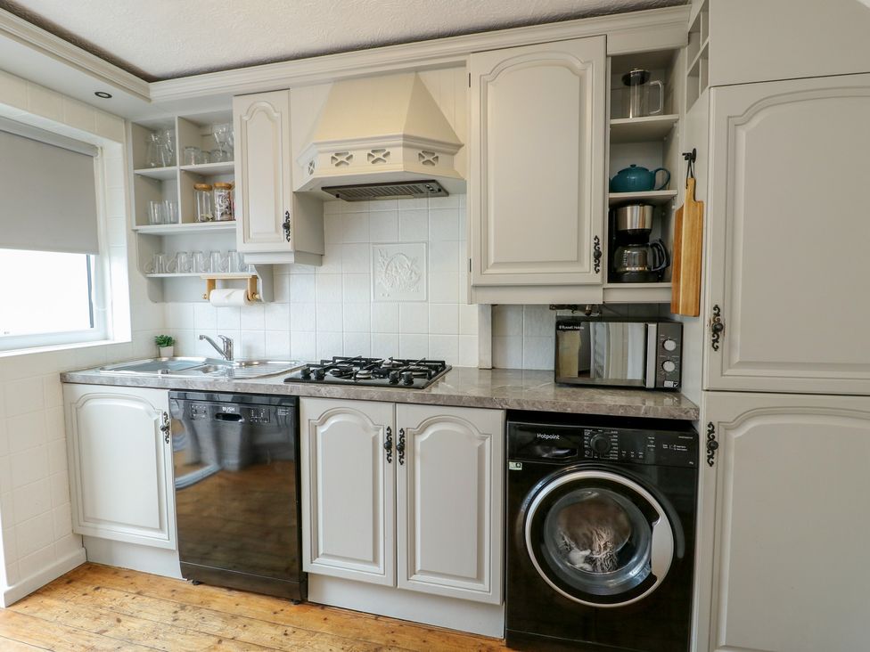 A kitchen with sink, stove, and appliances at Glasfryn in Holyhead