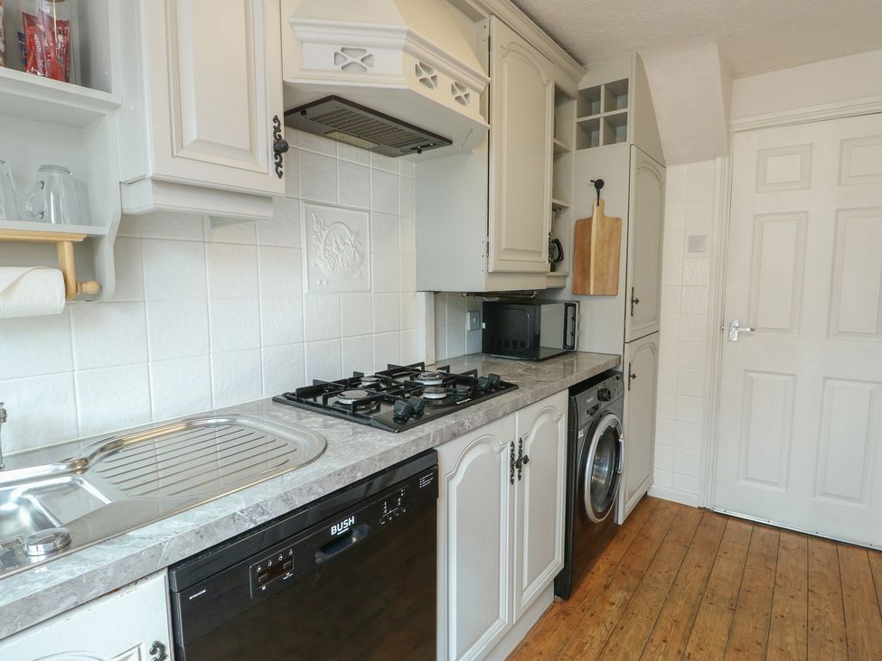 A kitchen with a sink, cooker, microwave, and washing machine at Glasfryn Holyhead