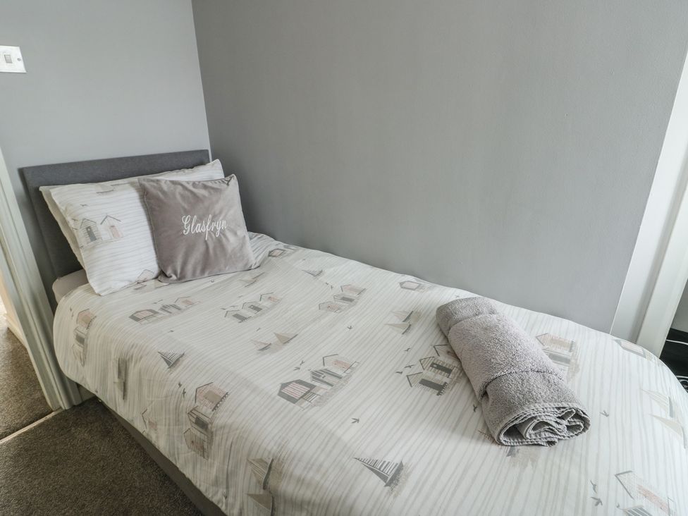 A bedroom with a single bed and towel at Glasfryn in Holyhead