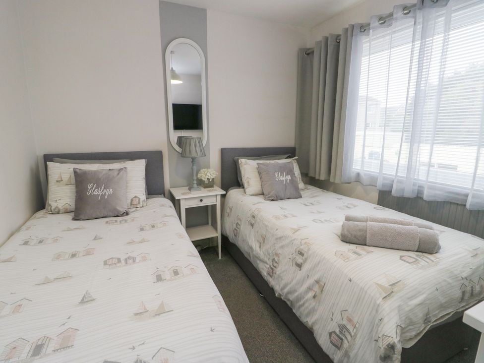 A bedroom with two single beds and a bedside table at Glasfryn in Holyhead