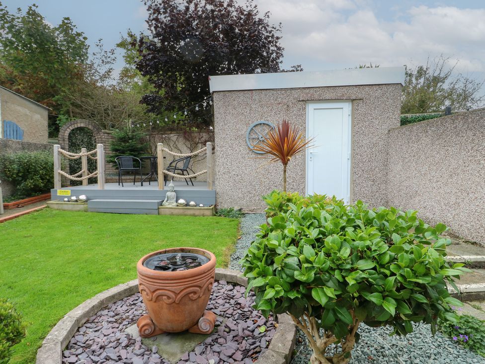 A garden with a flower pot, plants and a deck at Glasfryn in Holyhead