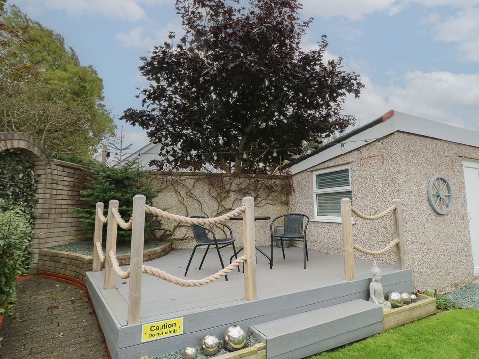 A garden with a deck and chairs near a shed at Glasfryn in Holyhead
