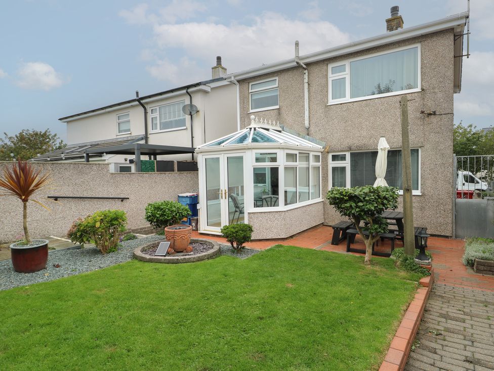 A garden with a conservatory and plants at Glasfryn Holyhead