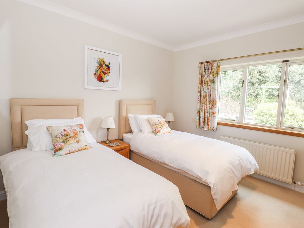 A bedroom with two single beds a window and floral curtains at Edencroft in Greystoke