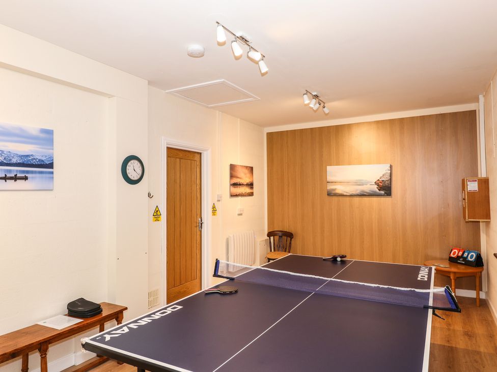 A room with a ping pong table a wooden door several landscape pictures a clock and a wooden bench at Edencroft in Greystoke