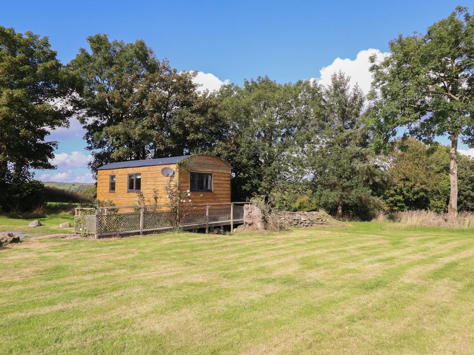 A wooden cabin with a satellite dish and fenced area at Stag Lodge Pod in Llanfair Caereinion