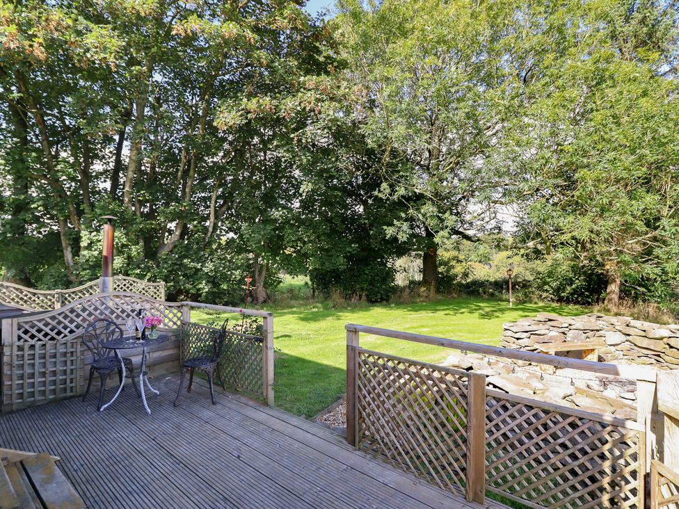 An outdoor area with a table and chairs on a deck at Stag Lodge Pod Llanfair Caereinion
