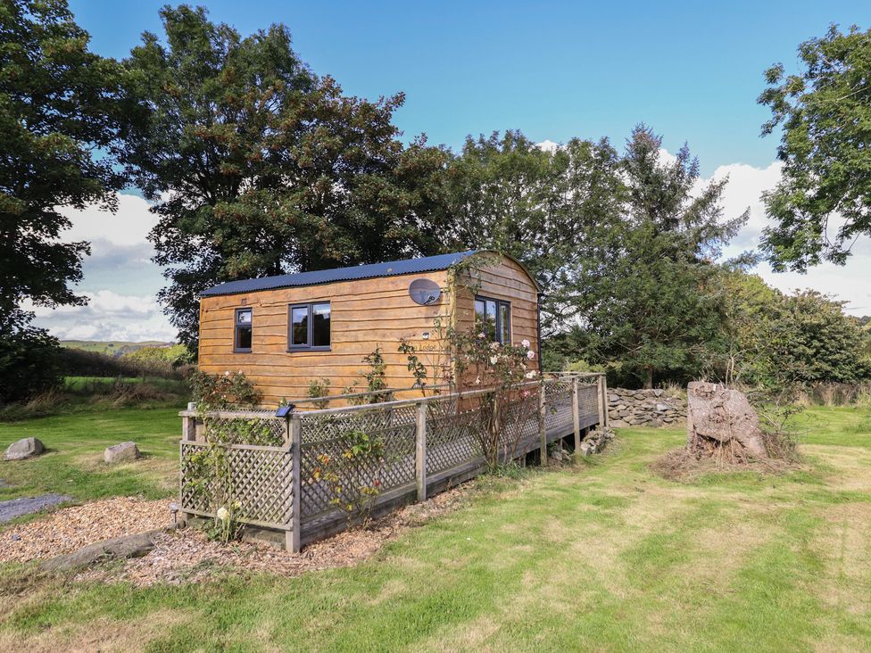 A wooden cabin with a deck and trees at Stag Lodge Pod Llanfair Caereinion