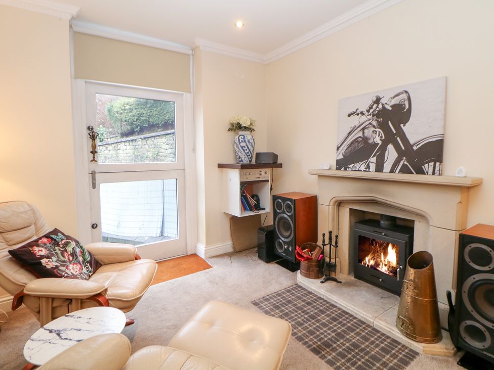 A living room with a fireplace and leather chair at Kirkham House Matlock Bath