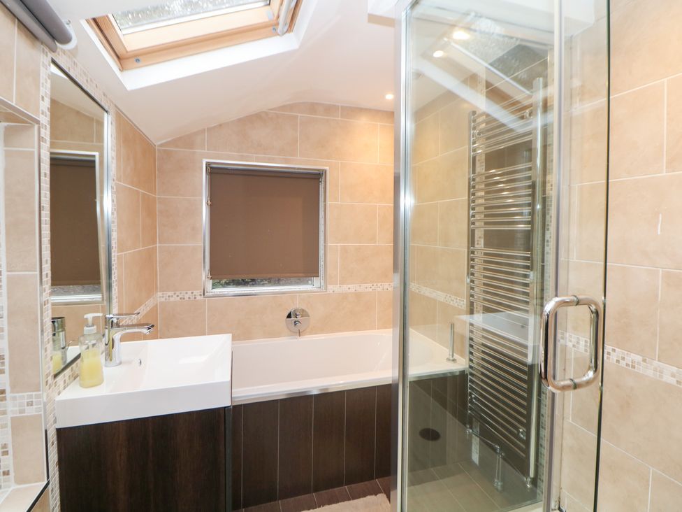 A bathroom with a bathtub, shower, sink, and towels at Kirkham House in Matlock Bath