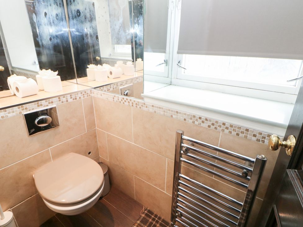 A bathroom with a toilet and mirror at Kirkham House in Matlock Bath