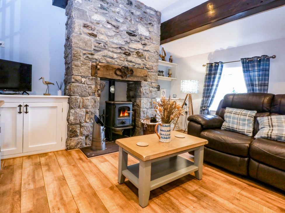 A living room with a fireplace and sofa at Cosy Cottage in Llandegfan near Menai Bridge