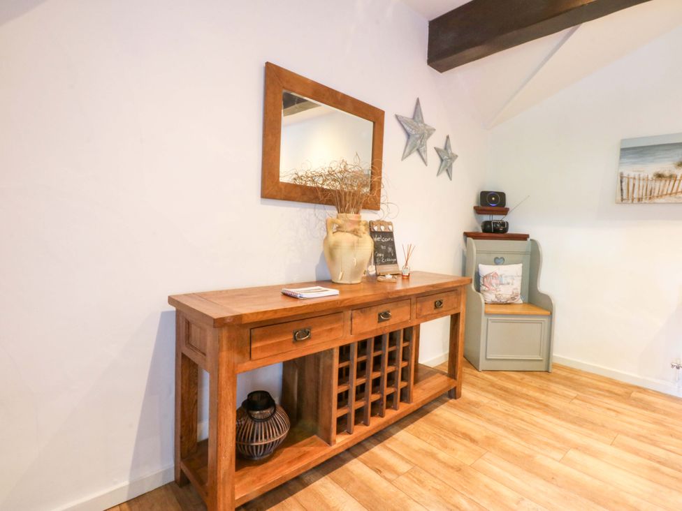 A console table with a mirror and vase at Cosy Cottage in Llandegfan near Menai Bridge
