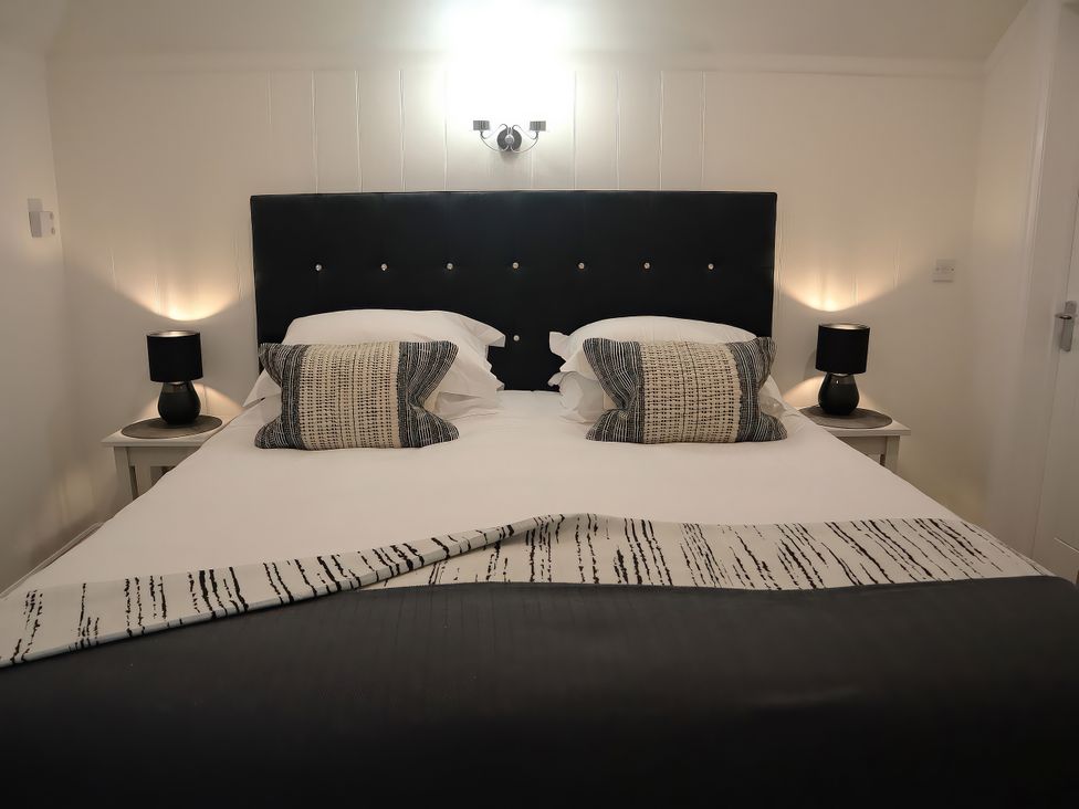 A bedroom with a bed and bedside tables at Lavender Barn in Crantock