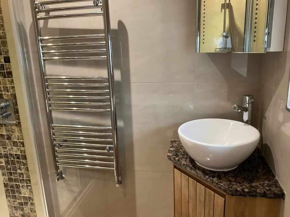 A bathroom with towel radiator and wash basin at Lavender Barn in Crantock