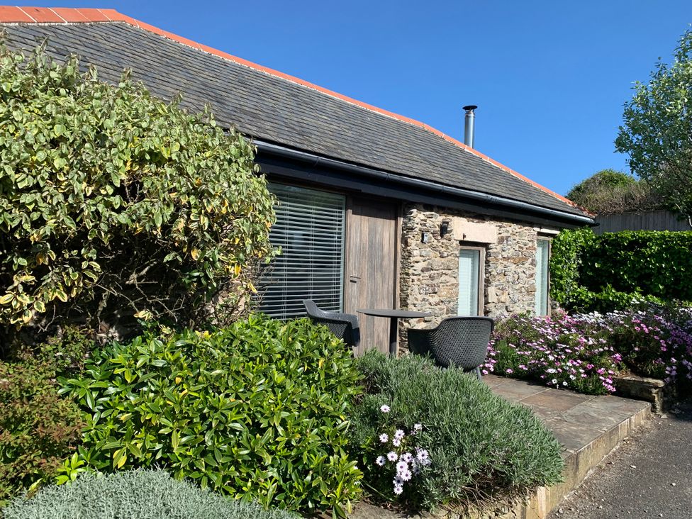 An outdoor seating area with flowers and shrubs at Lavender Barn Crantock