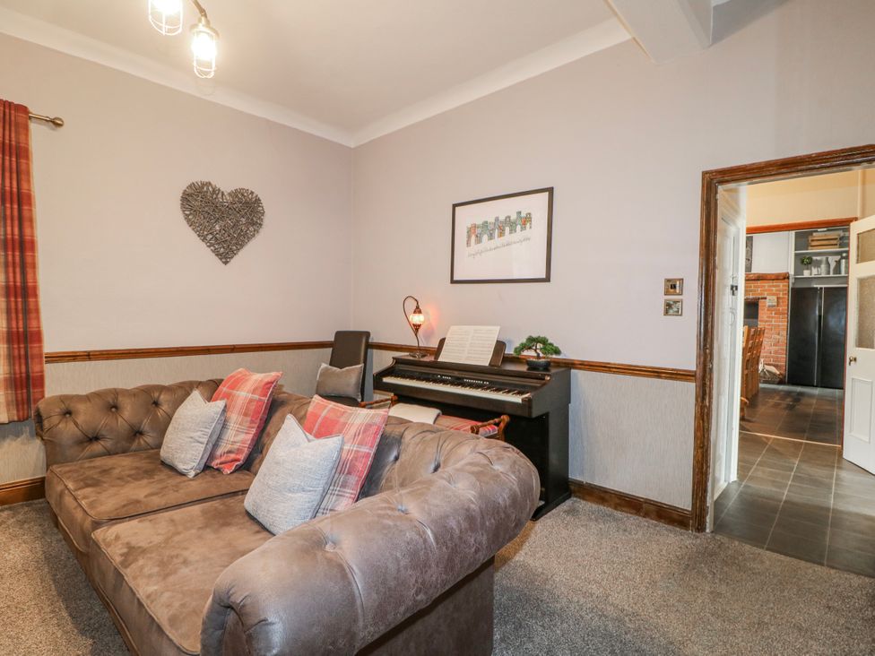 A living room with a piano and a sofa at Ley Fields Farm in Cheadle