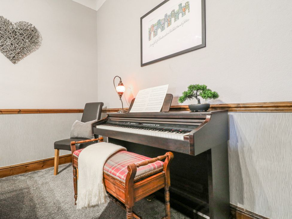 A music room with a piano and sheet music at Ley Fields Farm in Cheadle