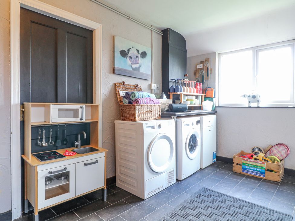 A laundry room with washers and a toy kitchen at Ley Fields Farm in Cheadle
