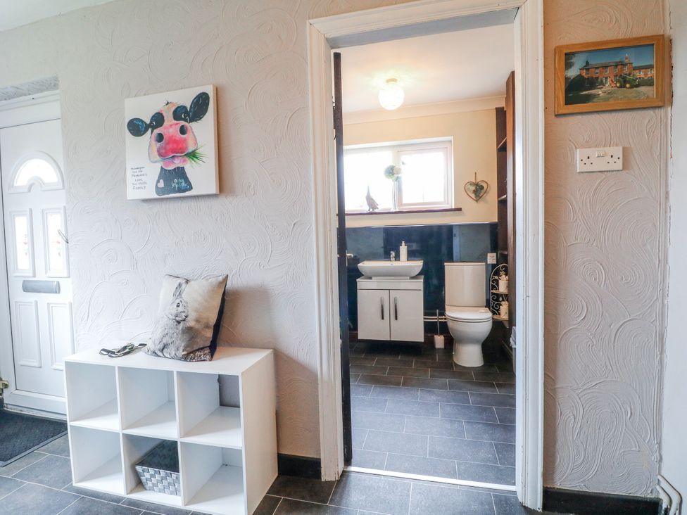 A hallway leading to a bathroom with a sink and toilet at Ley Fields Farm, Cheadle