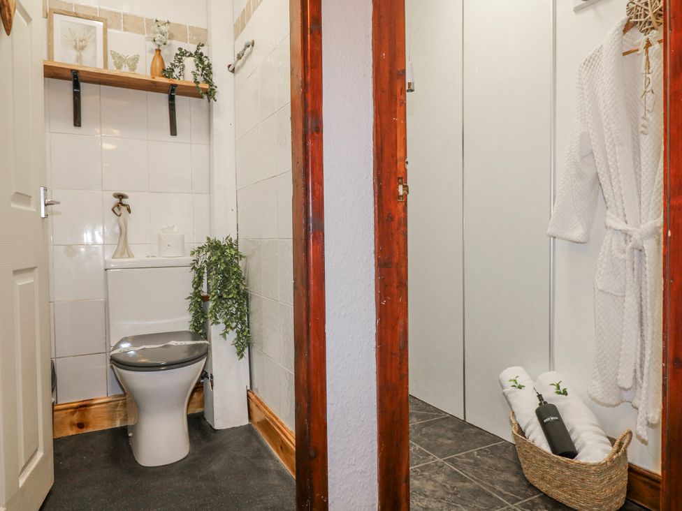 A bathroom with a toilet, shelf, and towels at Ley Fields Farm in Cheadle