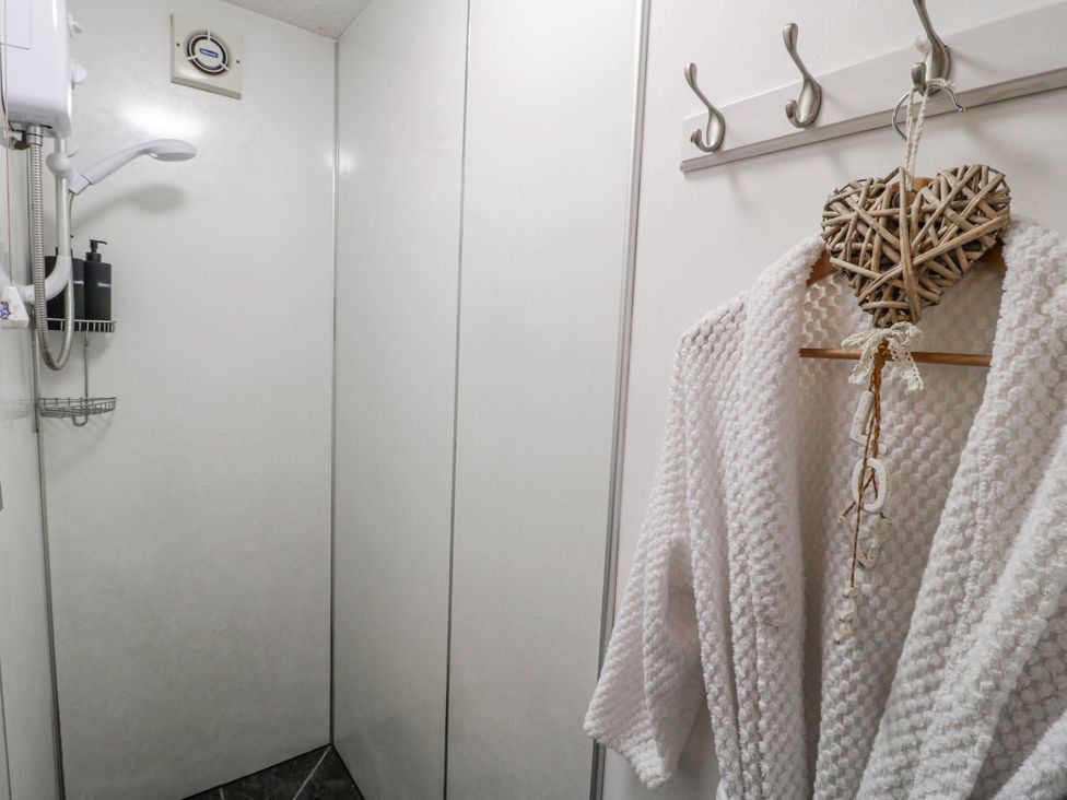 A shower area with a robe hanging and coat hooks at Ley Fields Farm in Cheadle