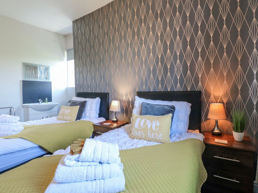 A bedroom with two beds and a nightstand at Ley Fields Farm, Cheadle