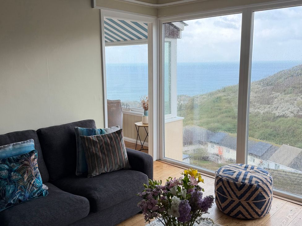A living room with a sofa and a flower arrangement at Ocean View in Downderry