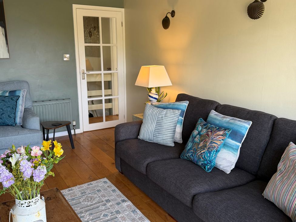 A living room with a sofa and flower vase at Ocean View in Downderry