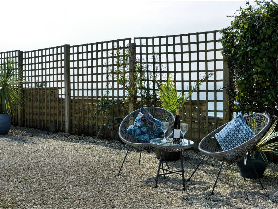 An outdoor seating area with armchairs and a table at Ocean View in Downderry