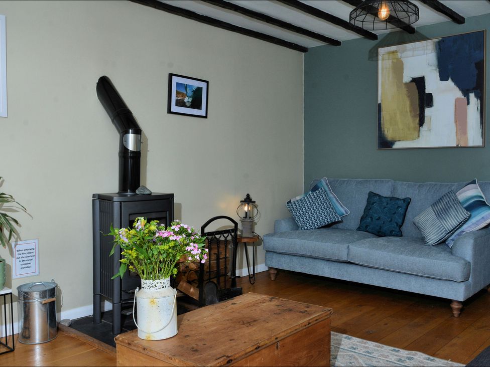A living room with a sofa and a wood stove at Ocean View in Downderry