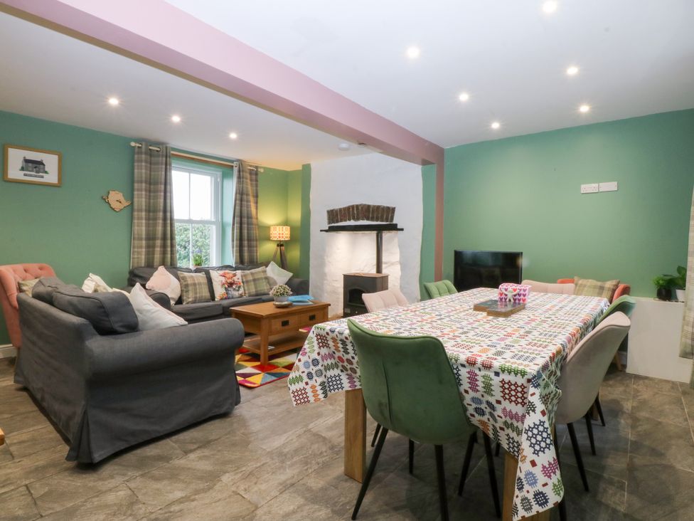 A living room with a sofa and dining table at Tregynrig Bach in Cemaes Bay