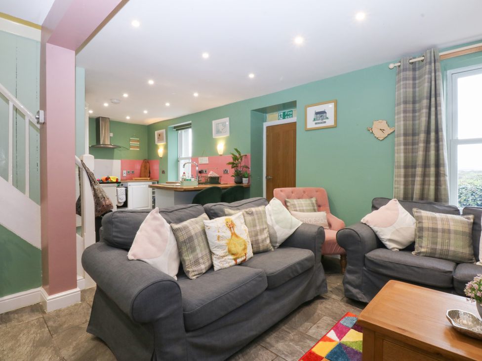 A living room with sofas and a kitchen area at Tregynrig Bach in Cemaes Bay