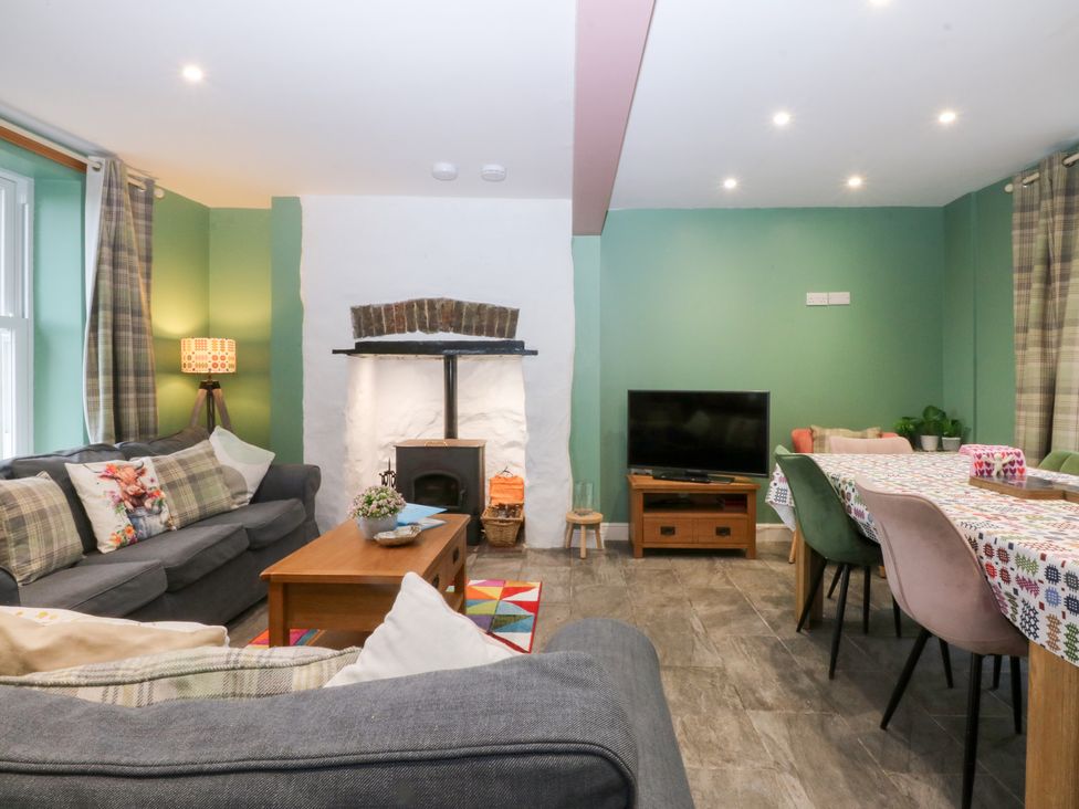 A living room with a sofa and dining area at Tregynrig Bach in Cemaes Bay