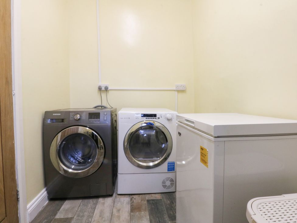 A utility room with washing machine dryer and freezer at Tregynrig Bach in Cemaes Bay