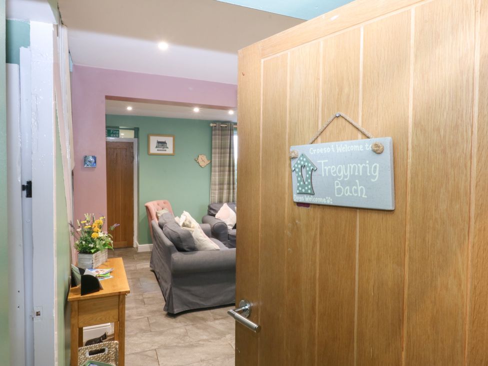 A living room with a welcome sign and sofa at Tregynrig Bach Cemaes Bay