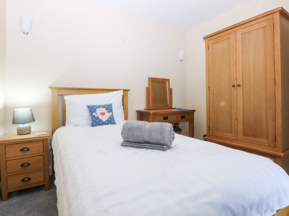 A bedroom with a bed and wooden furniture at Tregynrig Bach in Cemaes Bay