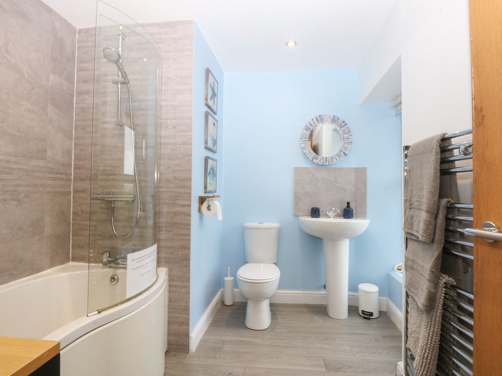 A bathroom with a shower, bathtub, toilet, and sink at Tregynrig Bach in Cemaes Bay