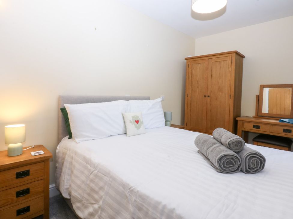 A bedroom with a bed and wardrobe at Tregynrig Bach Cemaes Bay