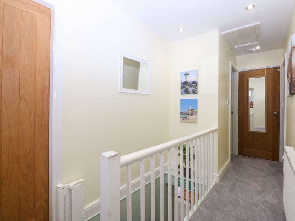 A hallway with a railing and pictures on the wall at Tregynrig Bach in Cemaes Bay