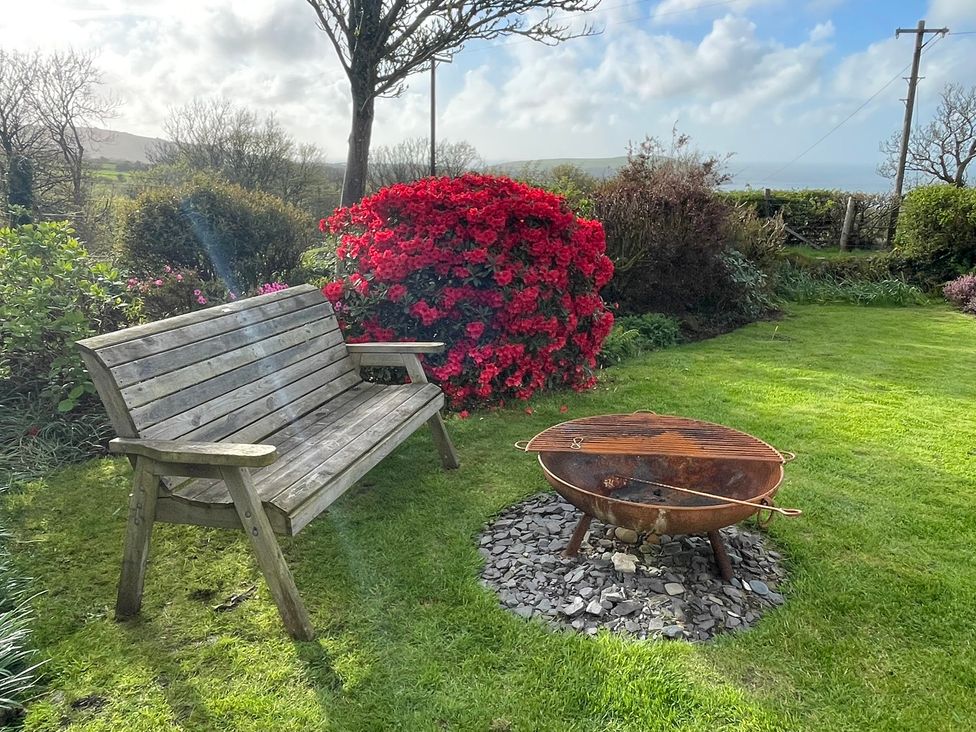 A garden with a wooden bench and a fire pit at Penllain Newport, Pembrokeshire