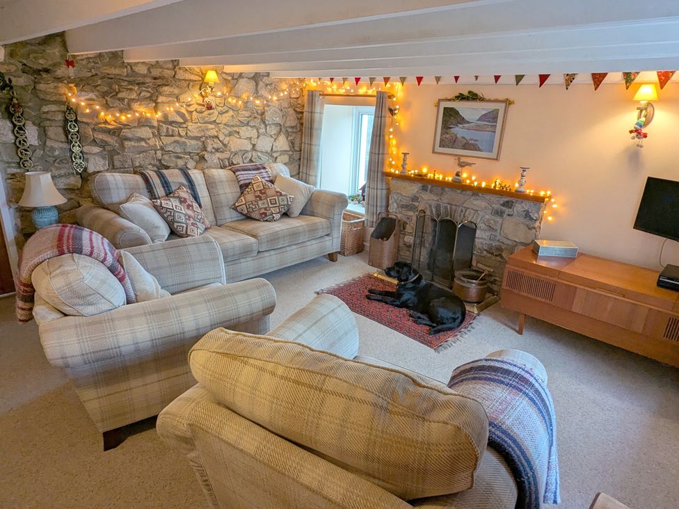 A living room with a sofa, armchair, and a television at Penllain in Newport, Pembrokeshire