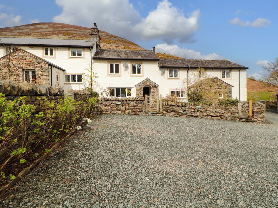 A house with a stone wall and gravel driveway at One Town End in Mungrisdale, Mosedale